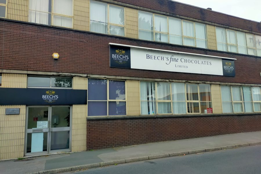 Exterior of Beech's Fine Chocolates factory building with signs.