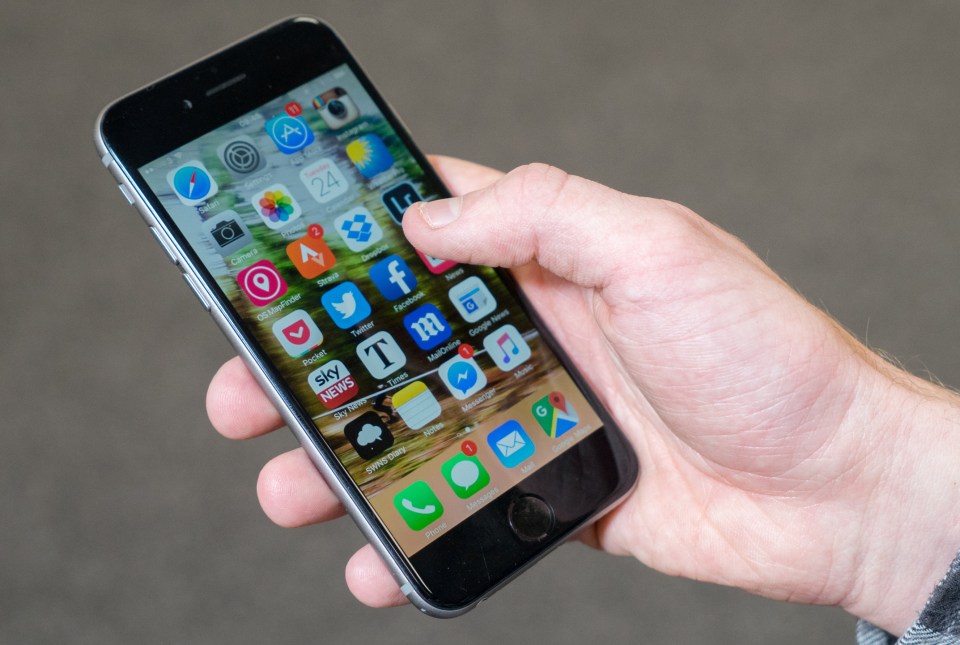 Hand holding smartphone displaying various apps.
