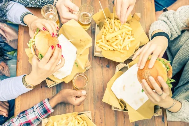 People eating burgers and fries at a table.