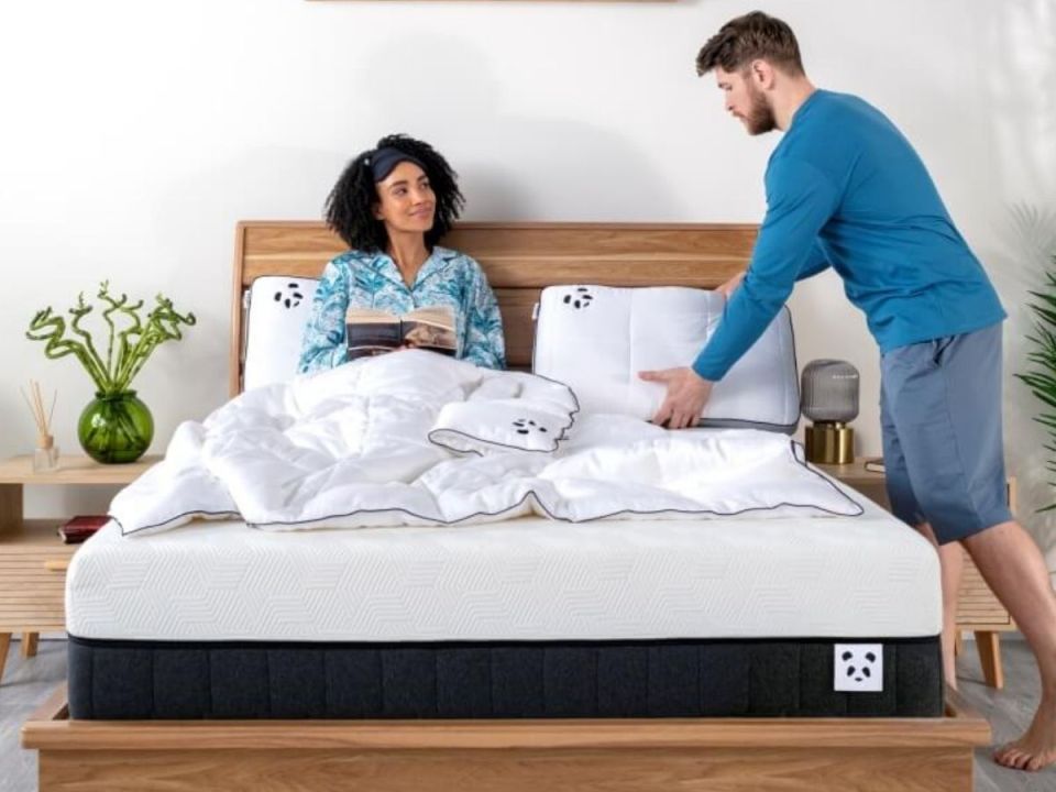 Couple making bed with new mattress and pillows.