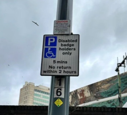 Sign indicating 5-minute parking for disabled badge holders only, with no return within 2 hours.