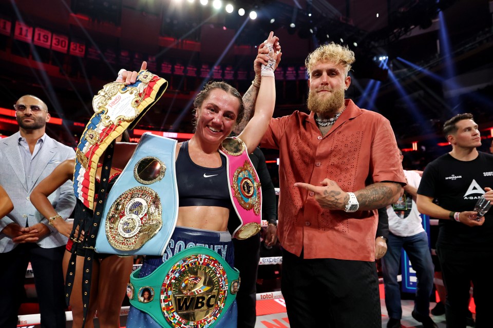 Ellie Scotney and Jake Paul posing after Scotney's victory, with Scotney holding multiple championship belts.