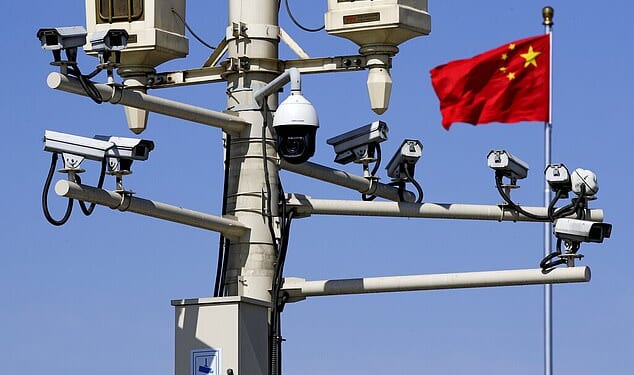 A Chinese national flag flutters near the surveillance cameras mounted on a lamp post in Tiananmen Square in Beijing