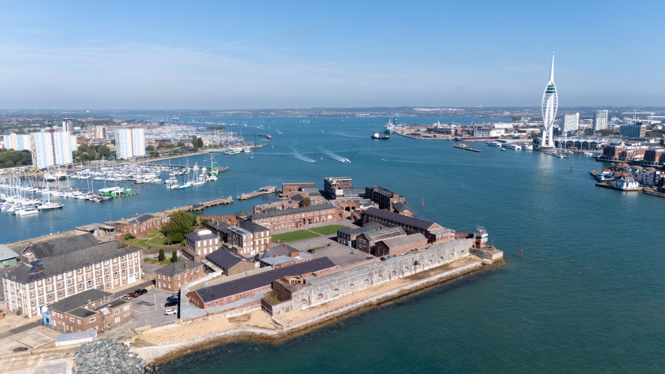 Aerial view of Fort Blockhouse, a disused military site in Gosport, England, located on a peninsula with a marina, buildings, and a tall white tower in the background.