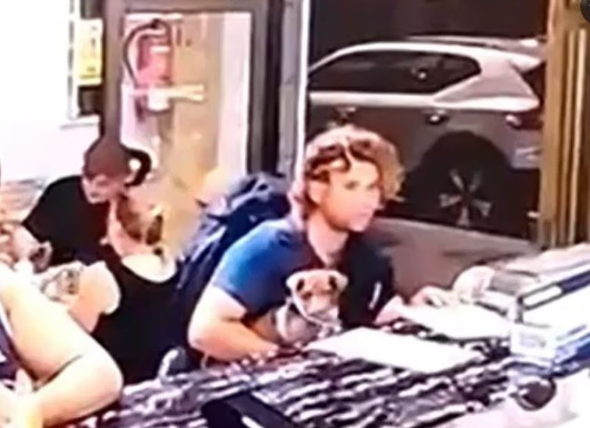 A man with curly hair and a dog in his lap at a counter.
