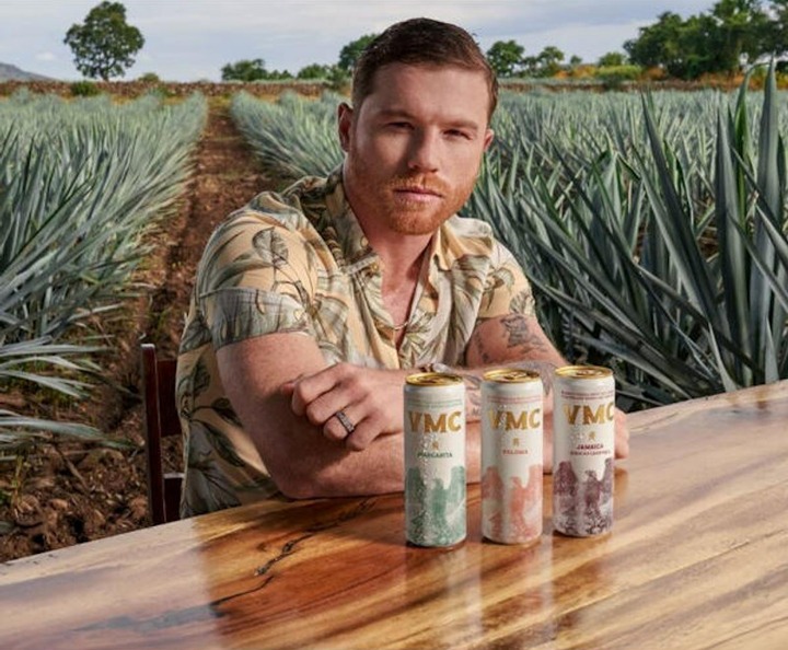 Man sitting at a table with three cans of VMC drink in front of him.