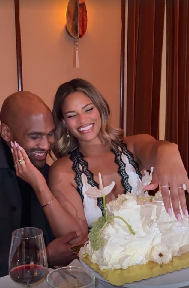 Kamie Crawford cutting a white cake with her fiance sitting beside her.