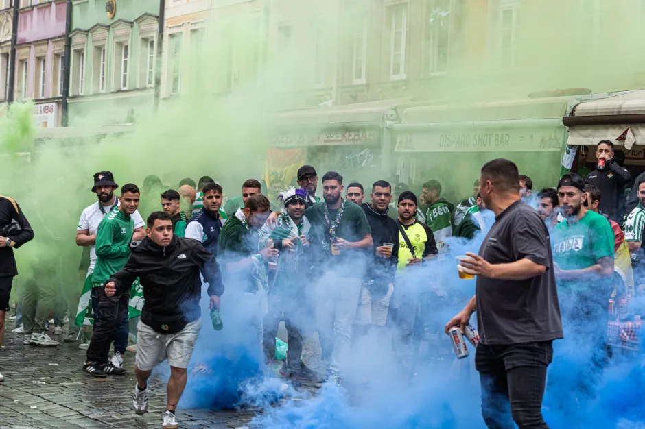 Sports fans amidst green and blue smoke bombs.