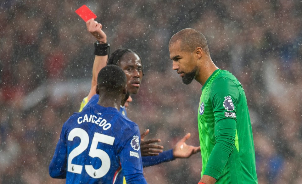 Referee Peter Bankes shows Chelsea goalkeeper Robert Sanchez a red card during a soccer match.