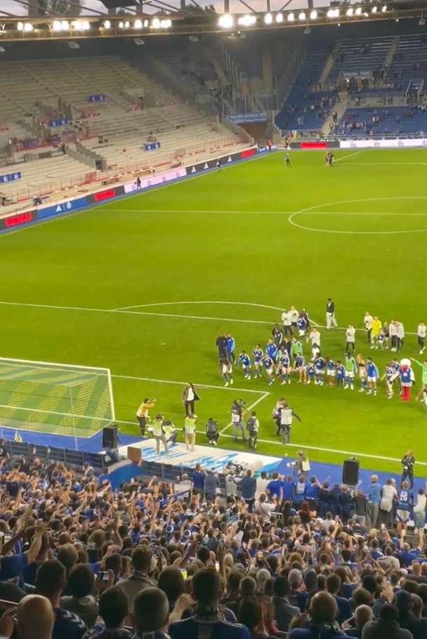 Soccer team on the field with cheering fans in the stands.
