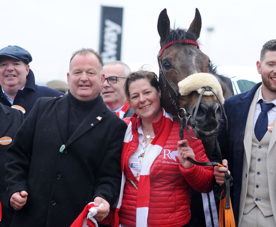 Trainer Patrick Neville, a woman, and another man smiling with the racehorse The Real Whacker at the Cheltenham Festival.