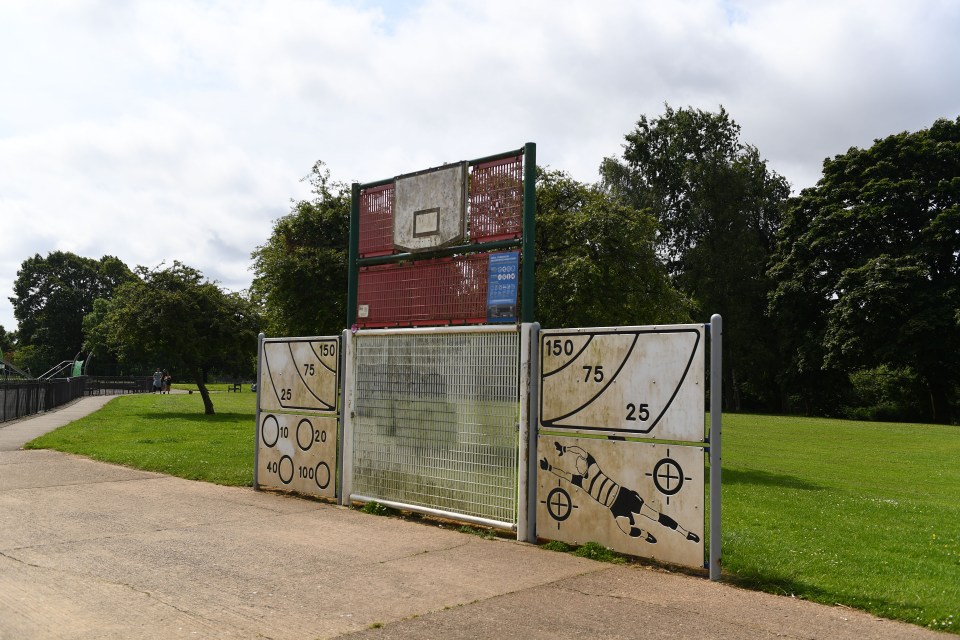 Park playground with a backboard and distance markers.