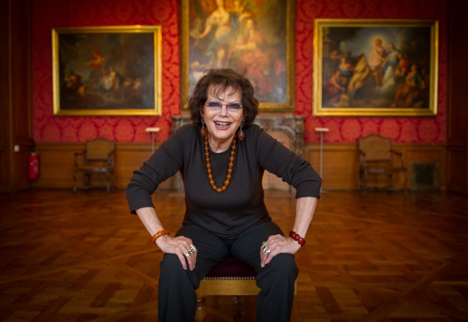 Italian actress Claudia Cardinale smiling while seated at a museum.
