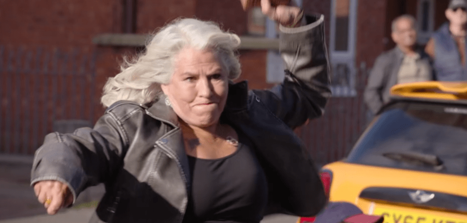 A woman with white hair and a black leather jacket runs, looking determined.