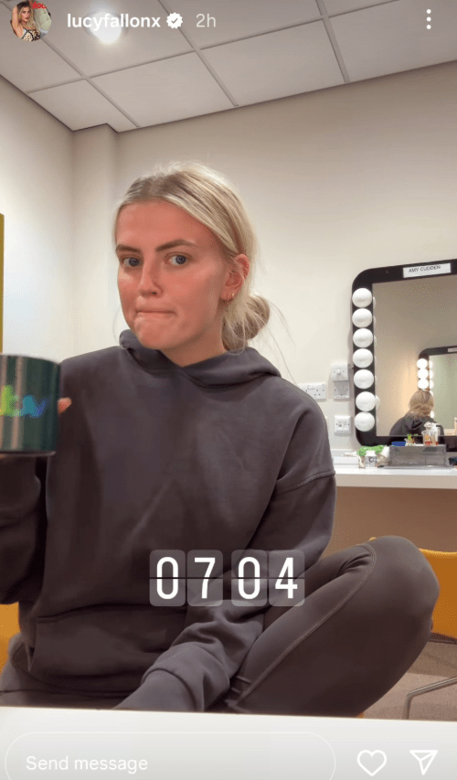 Woman in grey hoodie holding a mug.