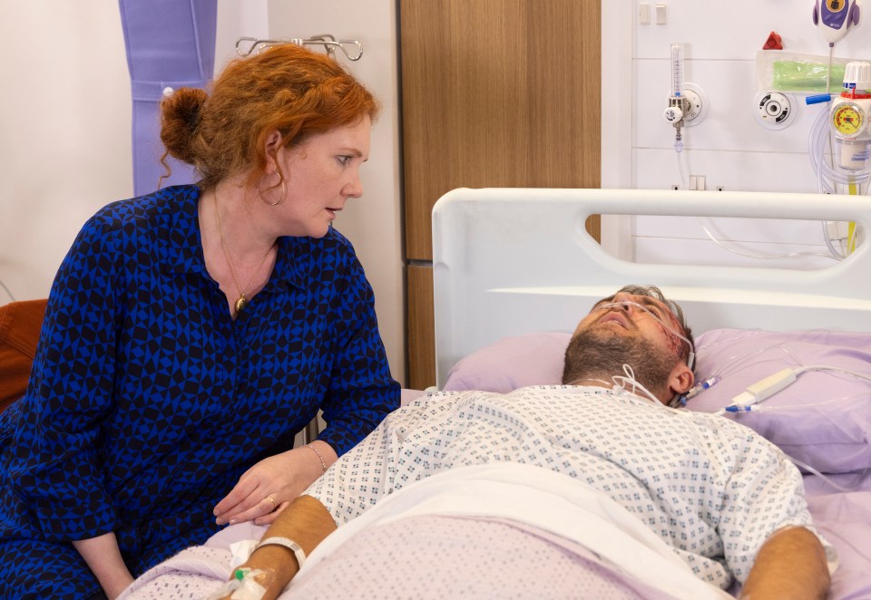 A woman sits by a man's hospital bed, looking concerned.