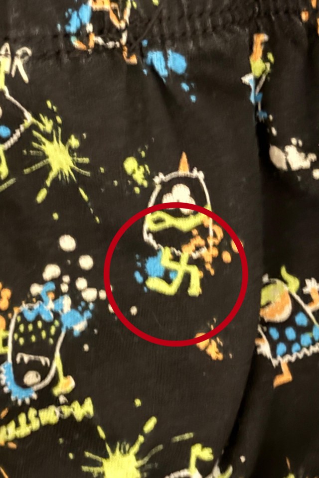 A red circle highlights a swastika-like symbol on black fabric with a pattern of monsters and paint splatters.