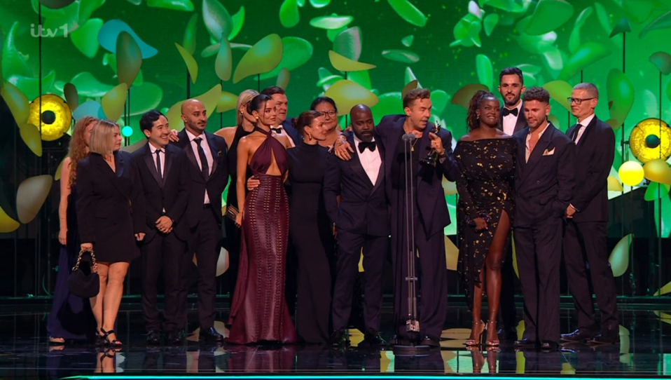 Group of people posing for a photo on stage, one person holding an award.