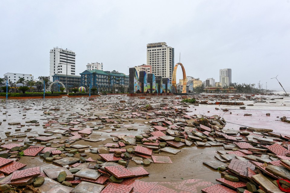 Cua Lo beach damaged after Typhoon Bualoi, with broken red and grey tiles scattered across the ground.