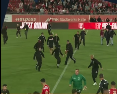 People running onto a soccer field.