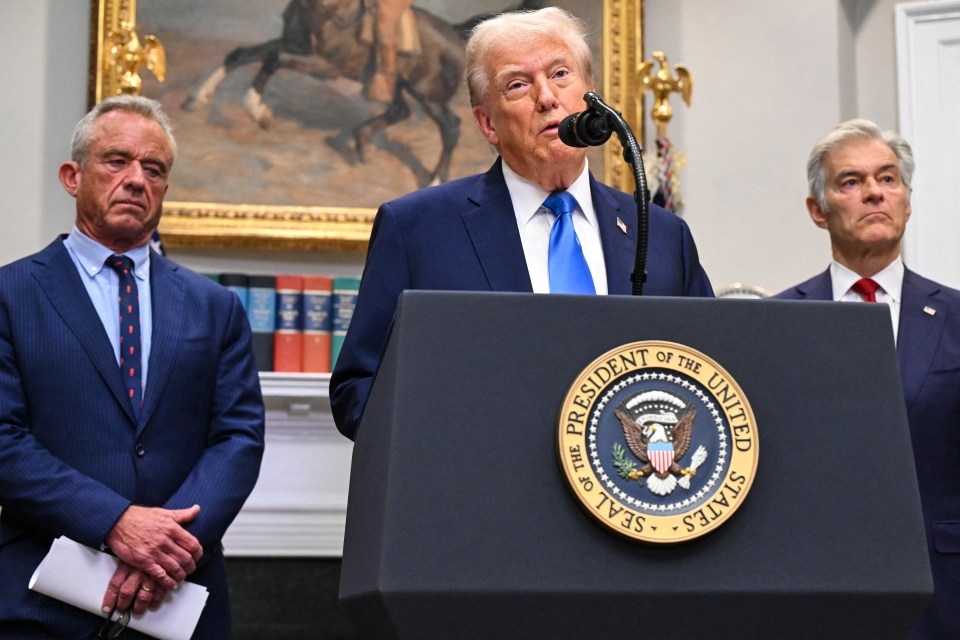US President Donald Trump speaks at a podium flanked by Secretary of Health and Human Services Robert F. Kennedy Jr. (left) and Medicare and Medicaid Administrator Mehmet Oz (right).