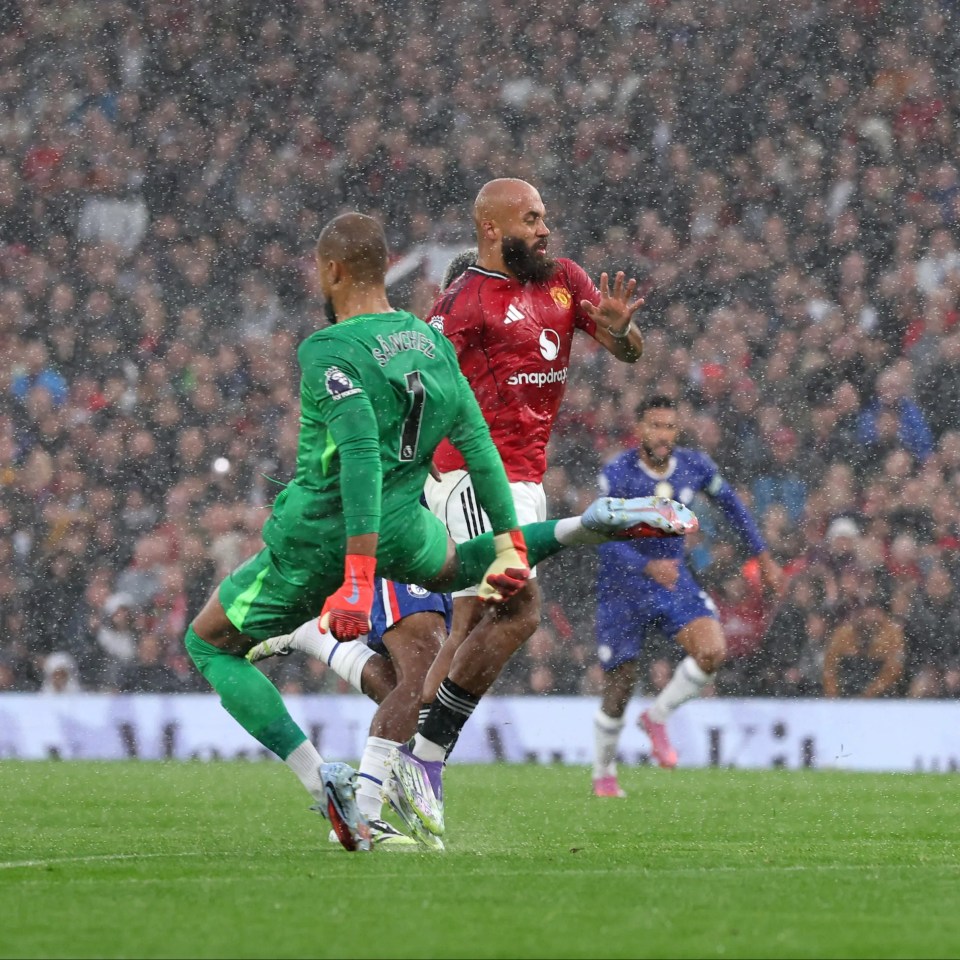 Manchester United player Bryan Mbeumo being fouled by Chelsea goalkeeper Robert Sanchez during a match.
