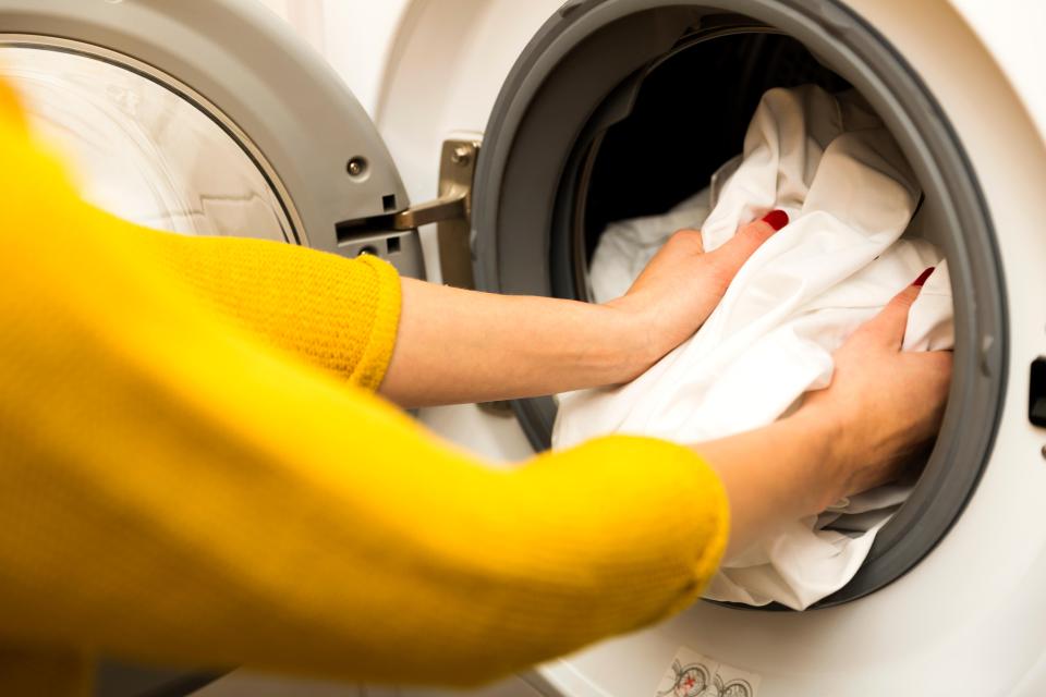Woman loading clothes into a washing machine.