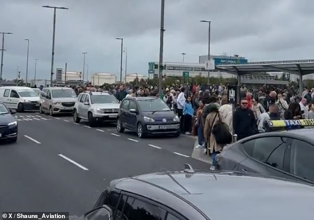 Dublin Airport was forced to evacuate today after an individual onboard a flight to New York was believed to have been travelling with 'detonators' in their luggage. Pictured: passengers wait outside Dublin Airport earlier today after being evacuated from the Terminal 2 building