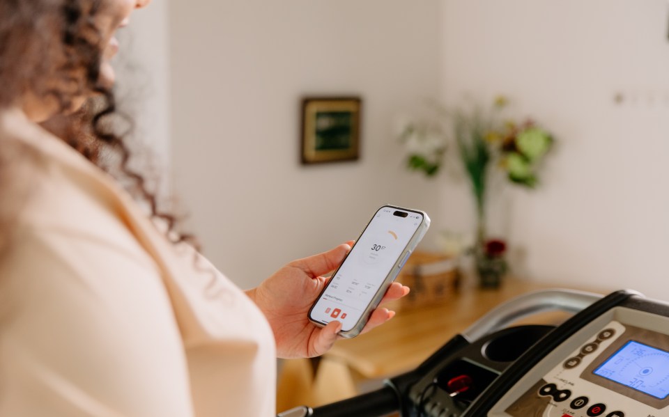 A person using their phone to monitor their workout progress on a treadmill.