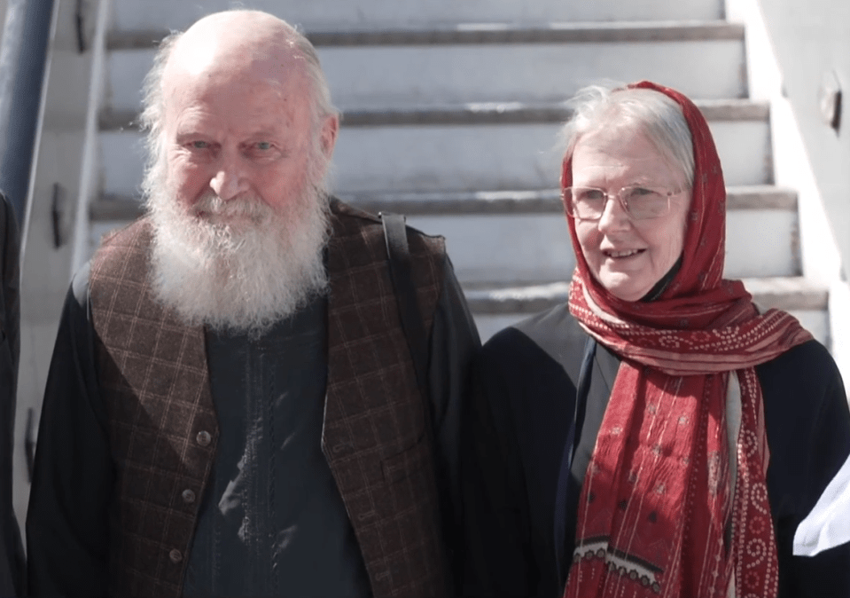 A bald man with a white beard and a woman with a red headscarf.