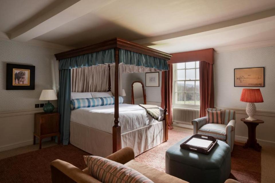 Bedroom with a four-poster bed and a sitting area with armchairs and an ottoman.