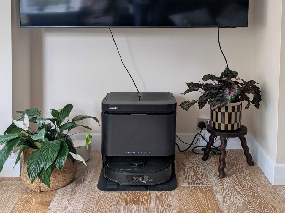 Eureka robot vacuum and charging station under a wall-mounted TV.