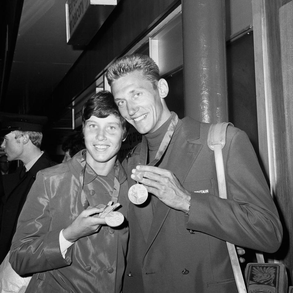 Olympic medalist Sheila Sherwood and her husband John Sherwood with their medals at Heathrow Airport.