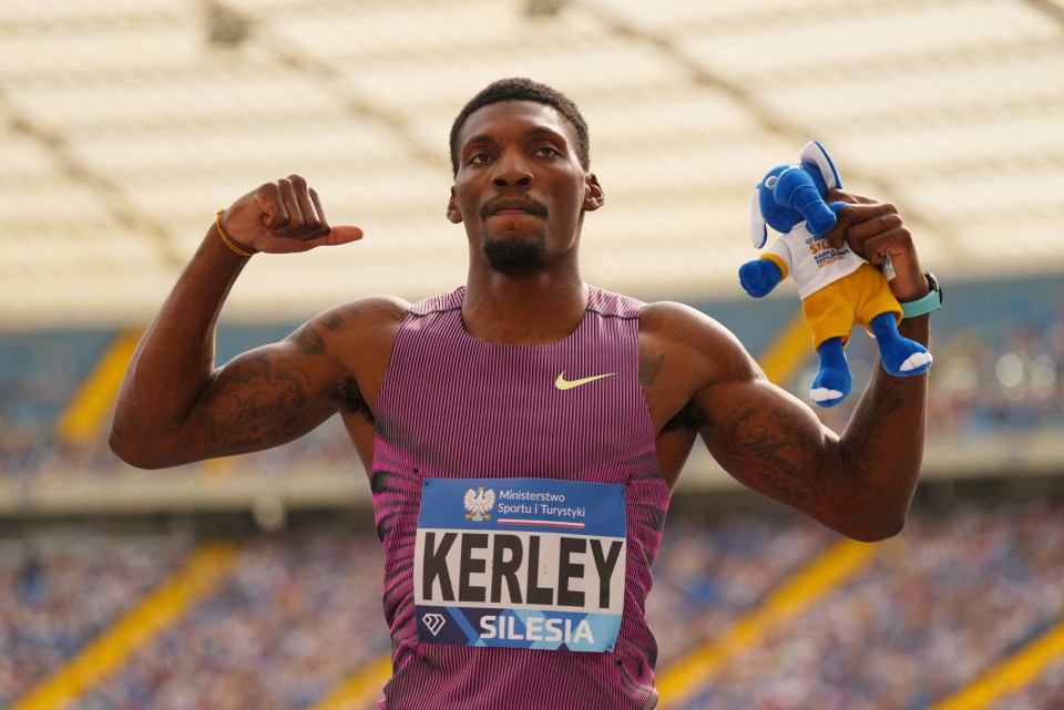 Fred Kerley flexing his bicep and holding a blue elephant toy.