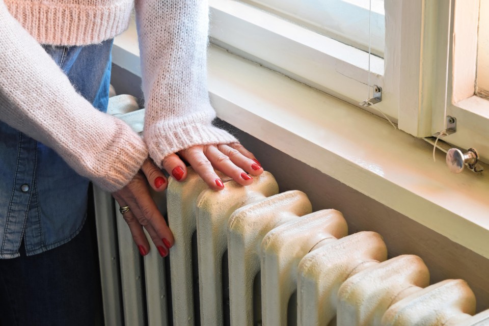 Hands warming on an iron radiator.