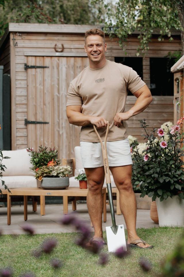 A man standing in a garden with a shovel.