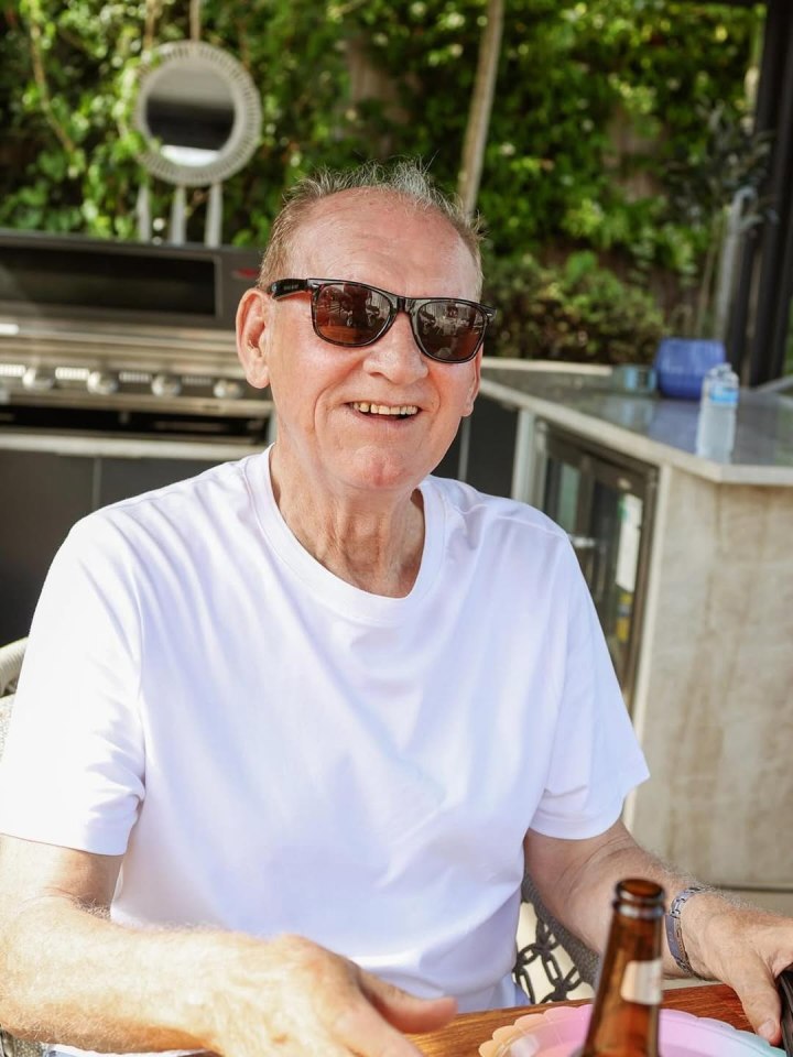 Smiling older man wearing sunglasses outdoors.