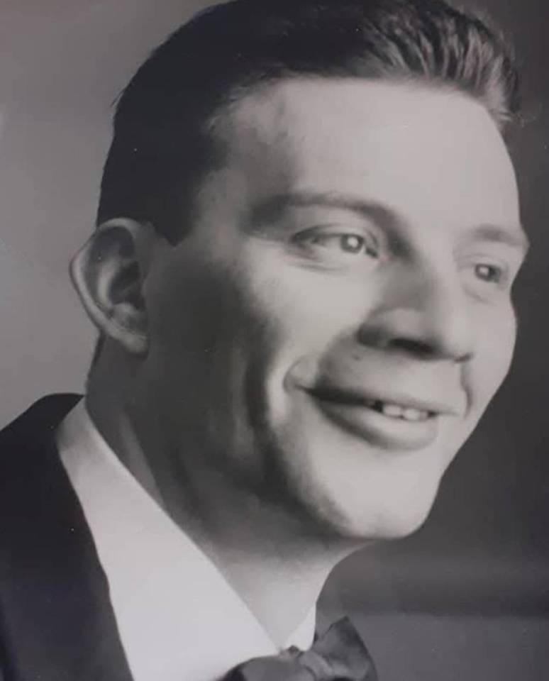 Black and white photo of Tony Scarrott as a young man, smiling.