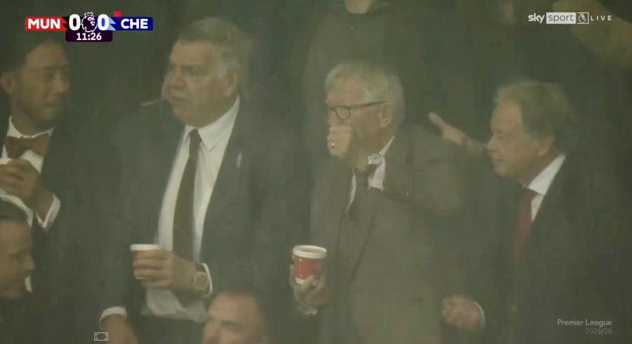Spectators in suits watching a football match.