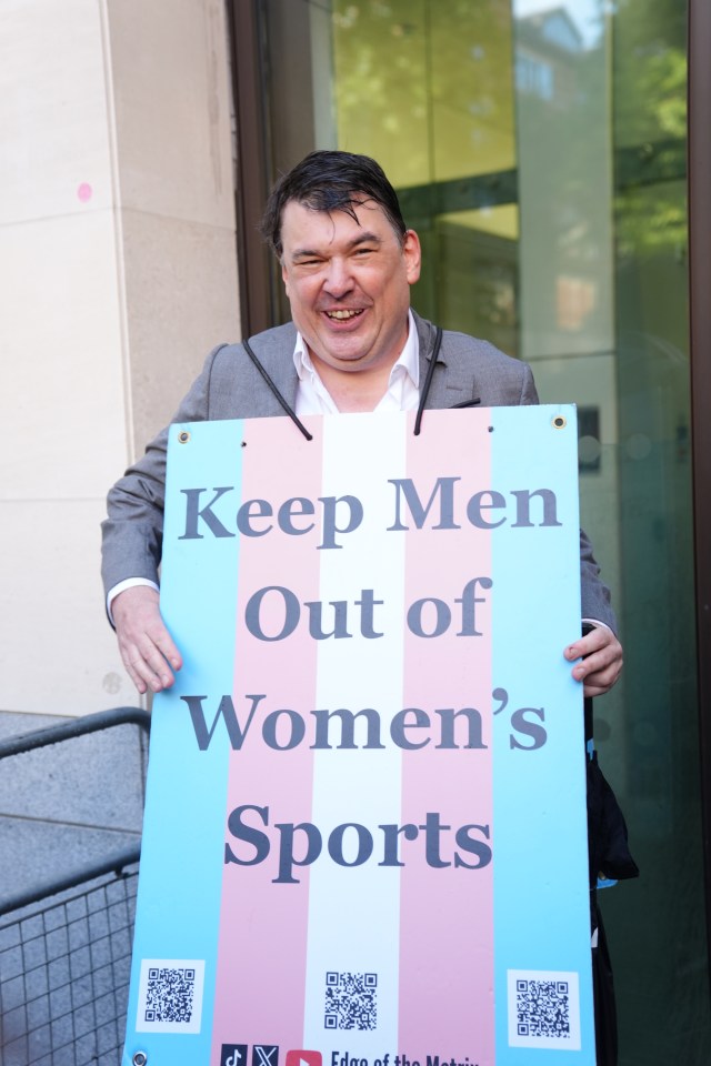 Graham Linehan holding a sign that says "Keep Men Out of Women's Sports".