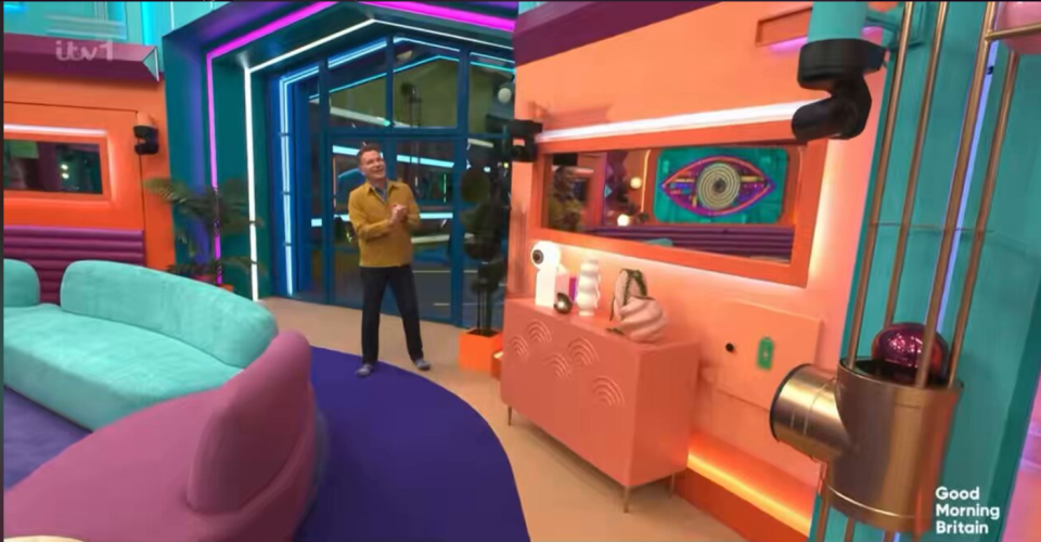 A man in a yellow jacket clapping in a brightly colored living room with a "Good Morning Britain" logo.