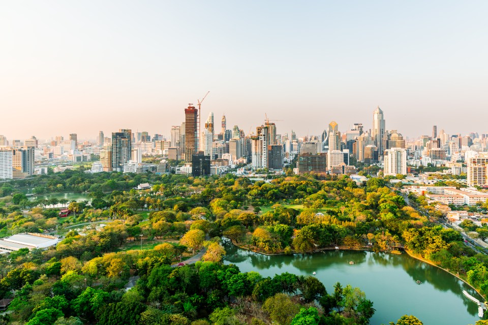 Aerial view of Lumpini Park with the Bangkok cityscape in the background.