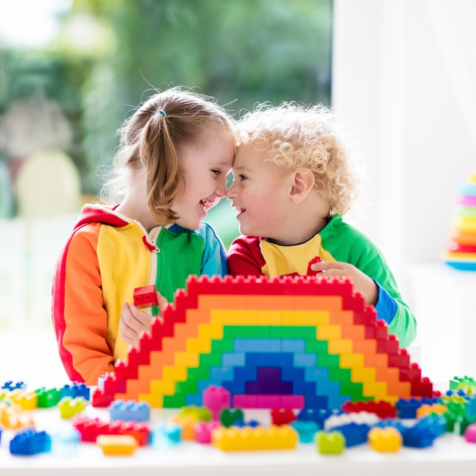 Two young children building a rainbow with colorful blocks.