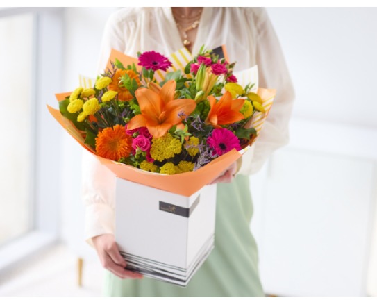 Birthday flowers in a box and on a table.
