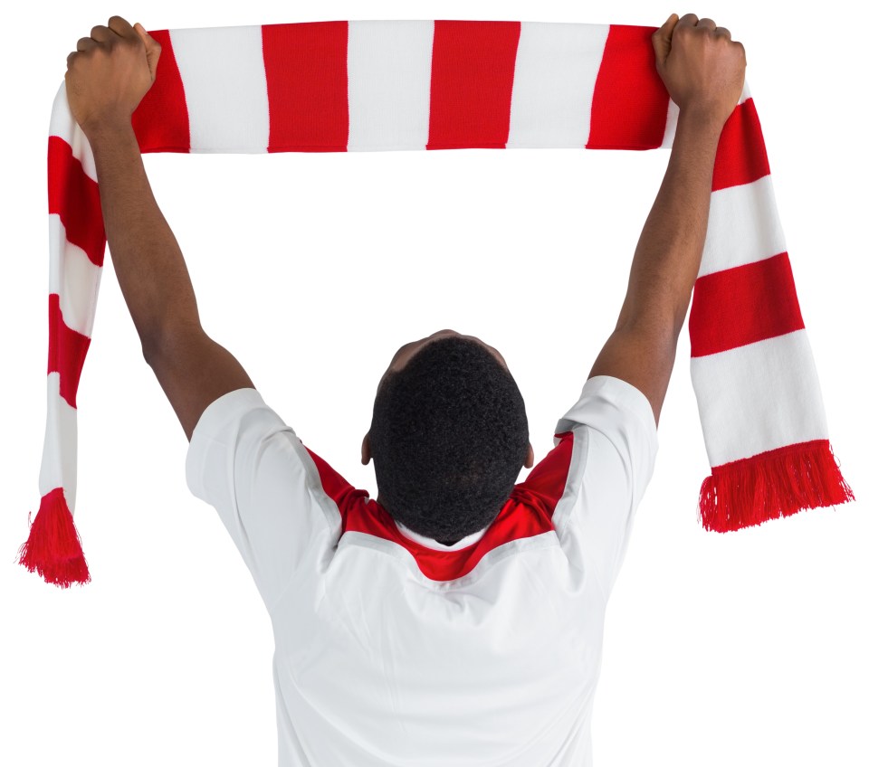 Rear view of a soccer fan holding up a red and white scarf.