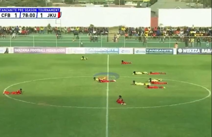 Soccer players lying on the field during a bee swarm.