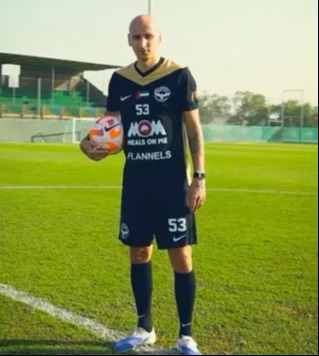 Man in a black and gold soccer uniform with a soccer ball.