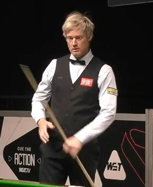 A snooker player in a black vest and bow tie holding a cue stick.