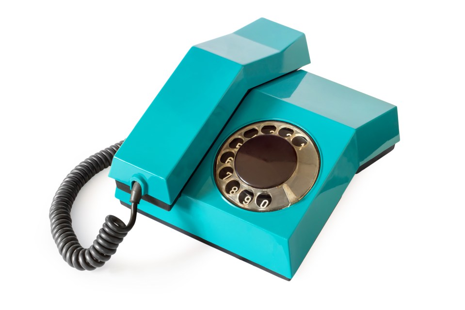 An old turquoise rotary telephone with the receiver resting on the base, on a white background.