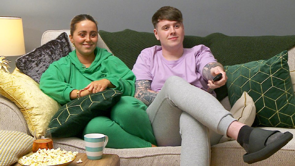 Photo of a young couple sitting on a couch, watching television.